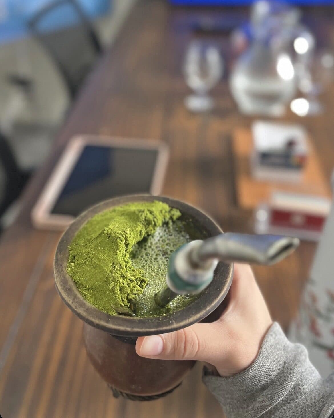 Mão segurando uma cuia de chimarrão sobre a mesa do escritório da Abarca