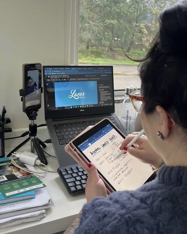 Integrante da Abarca escrevendo à mão num tablet, diante do notebook